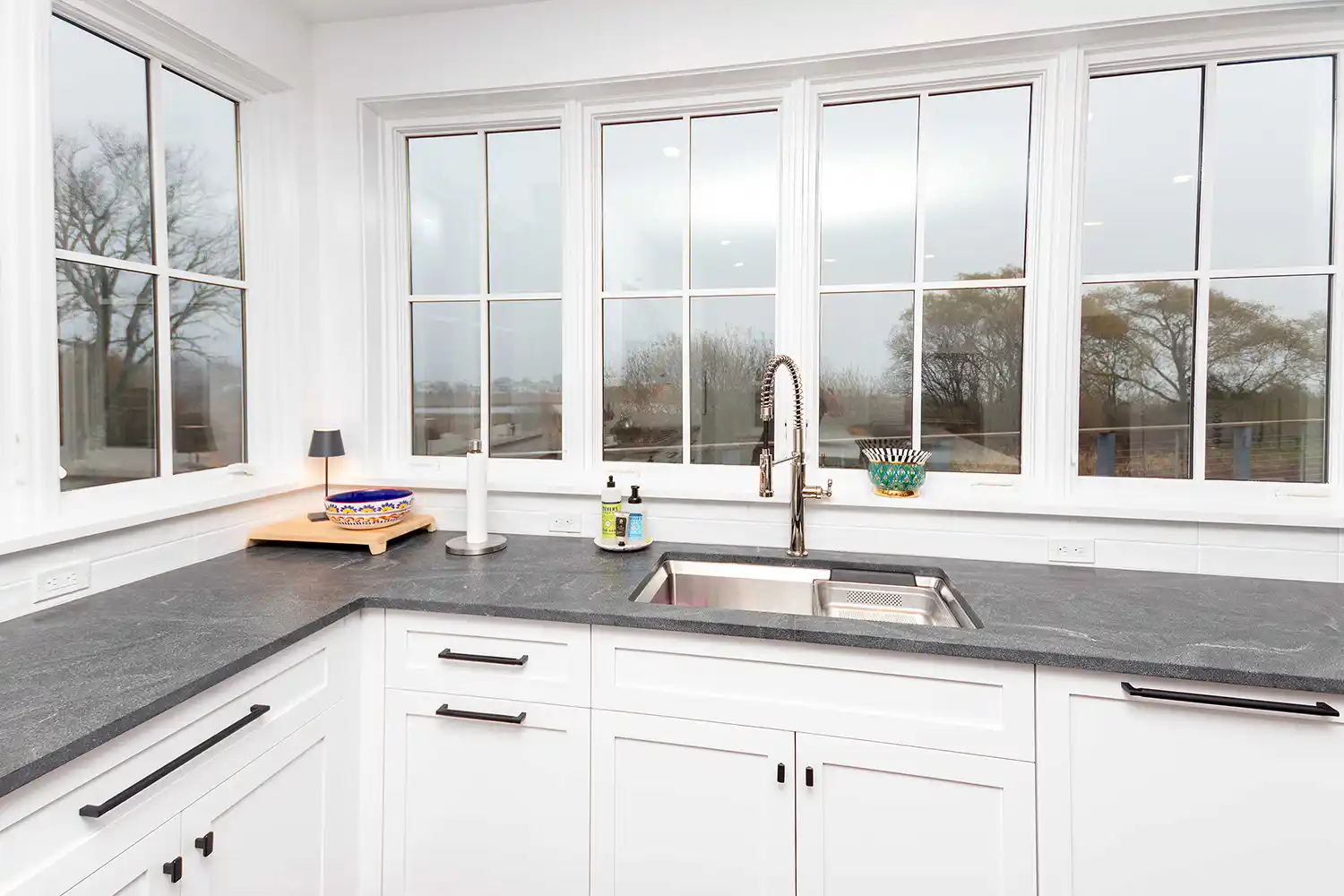 Kitchen counters and sink running under a long line of windows