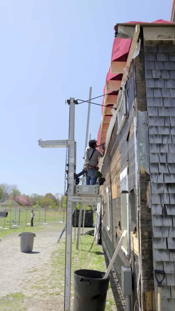 PJR carpenter on pump-jack scaffolding rebuilding the eave and rafter tails on the storage barn
